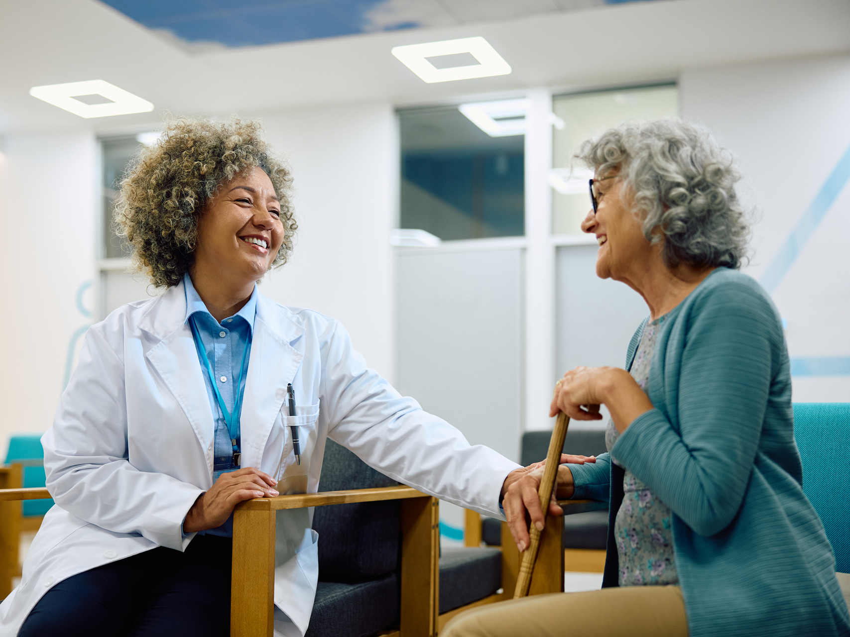 A doctor is talking to an elderly woman in a hospital waiting room.