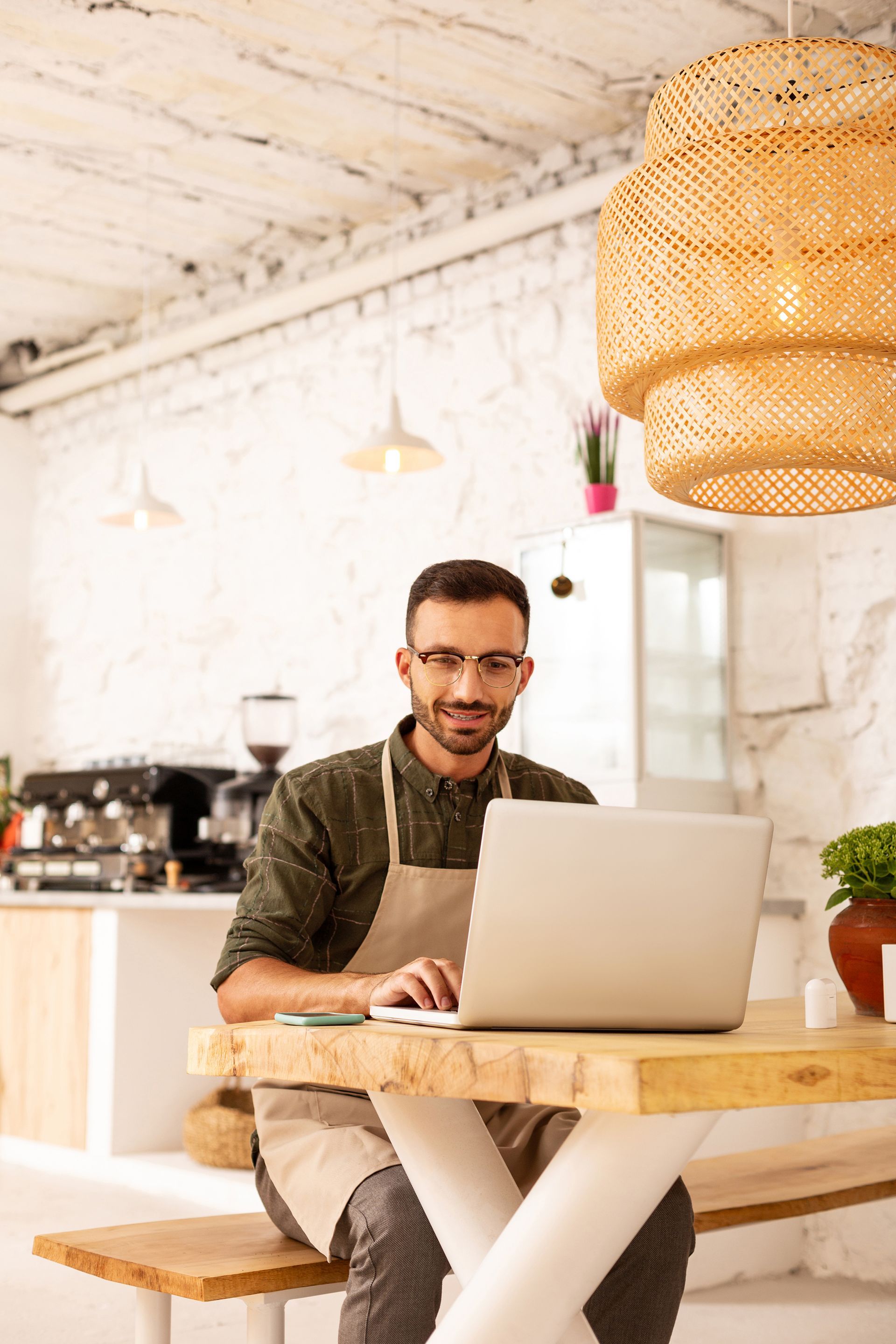 A man is sitting at a table using a laptop computer.
