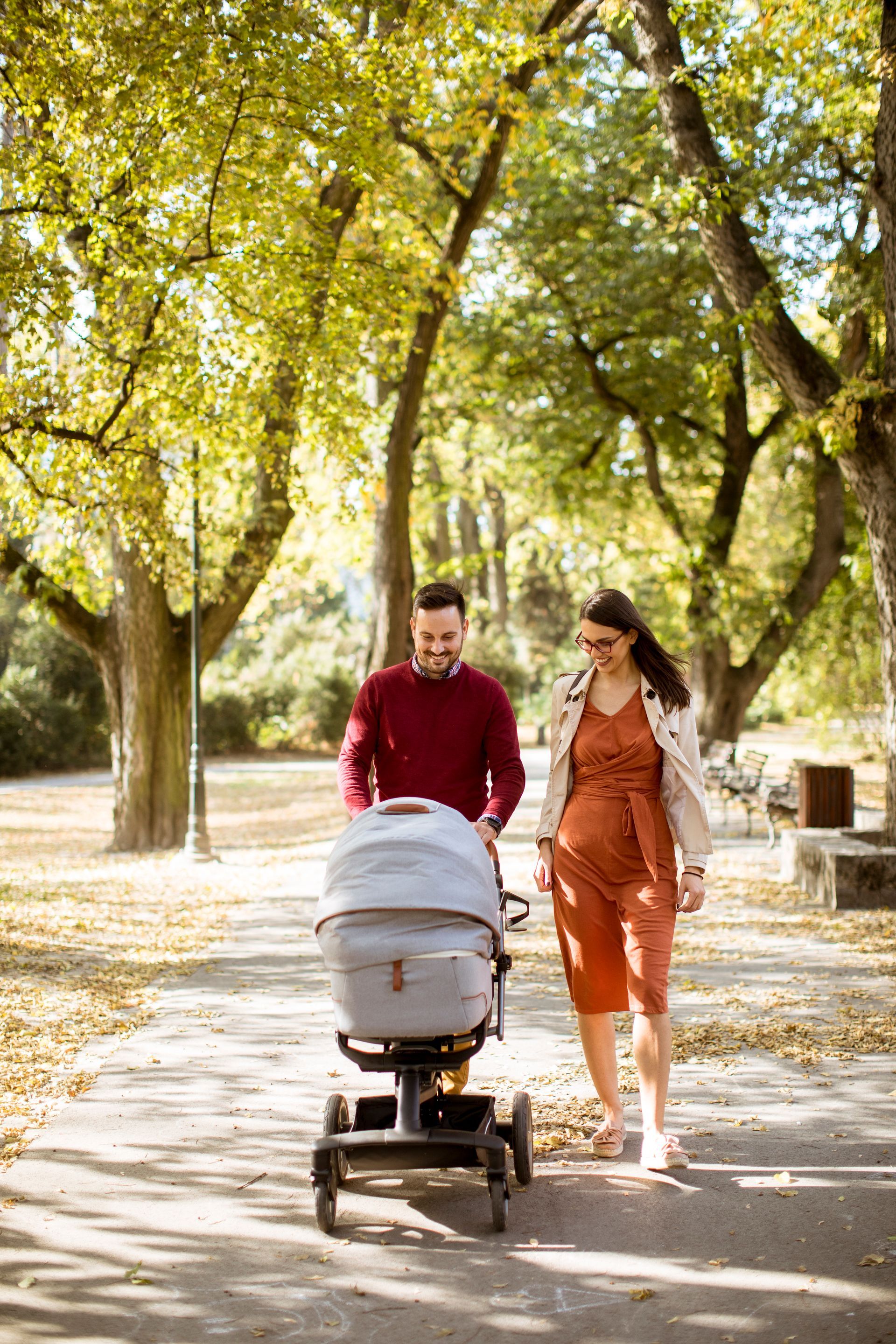A man and woman are pushing a stroller in a park.