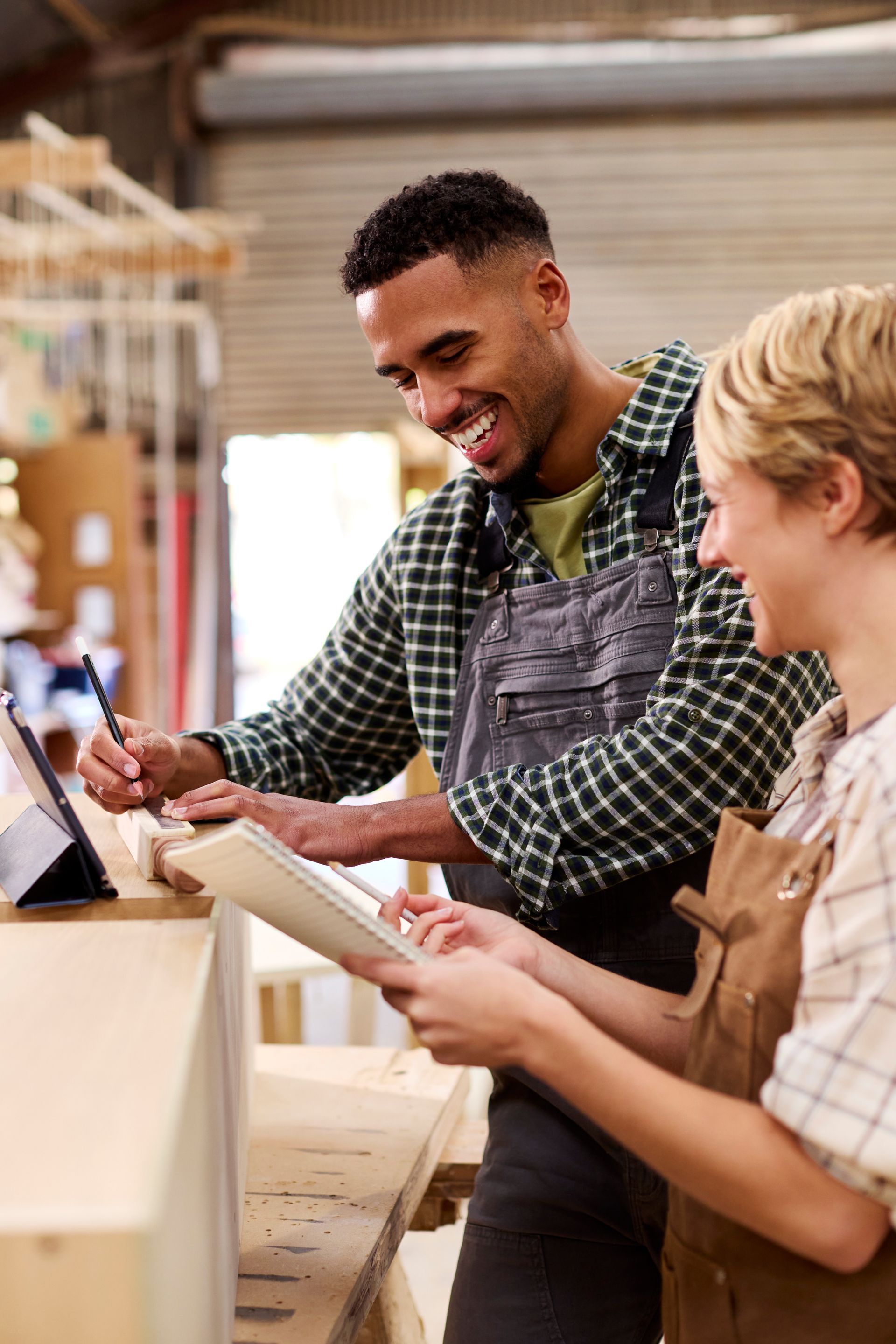 A man and a woman are looking at a tablet in a workshop.