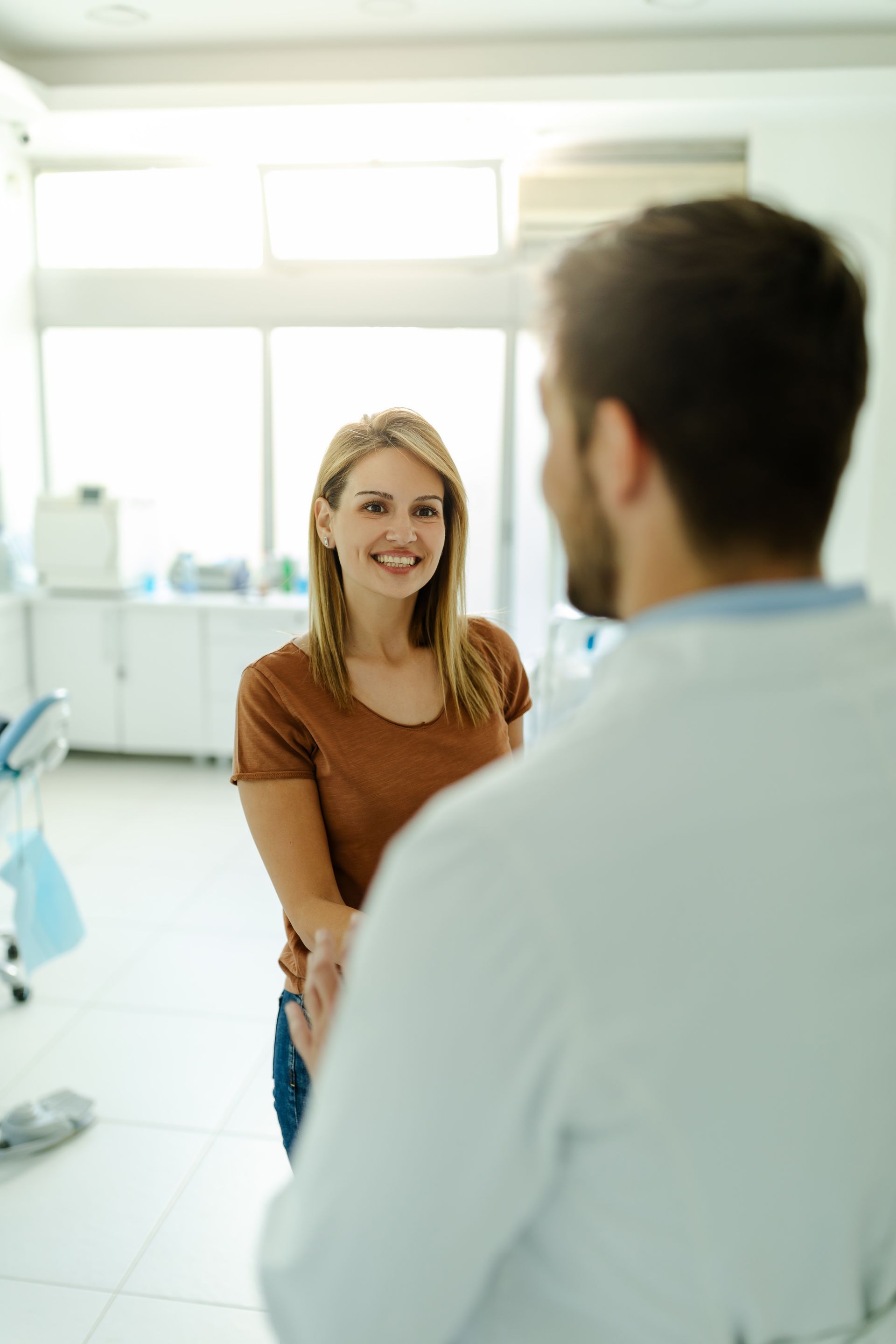 A woman is talking to a dentist in a dental office.