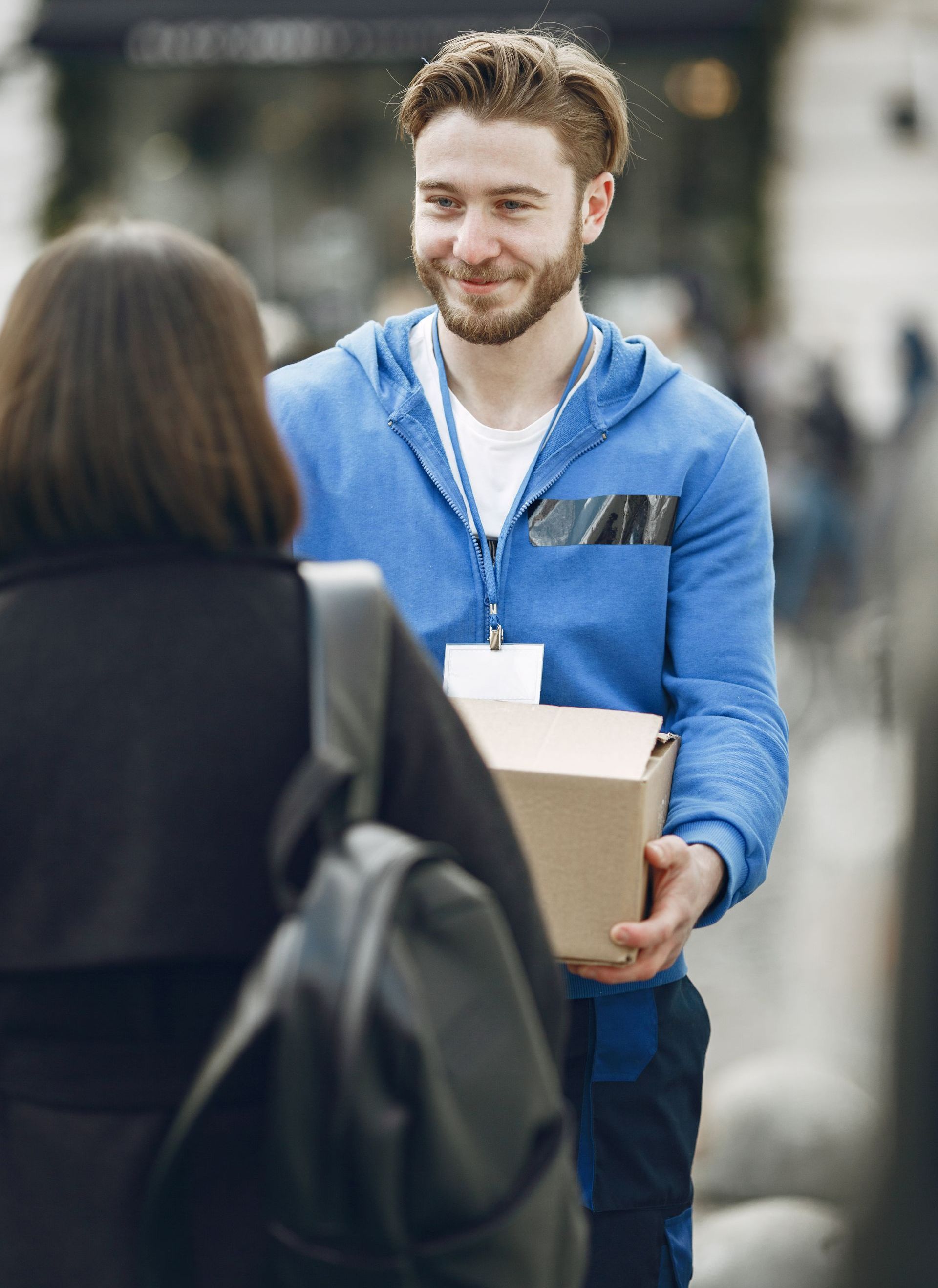 A man is giving a box to a woman on the street.