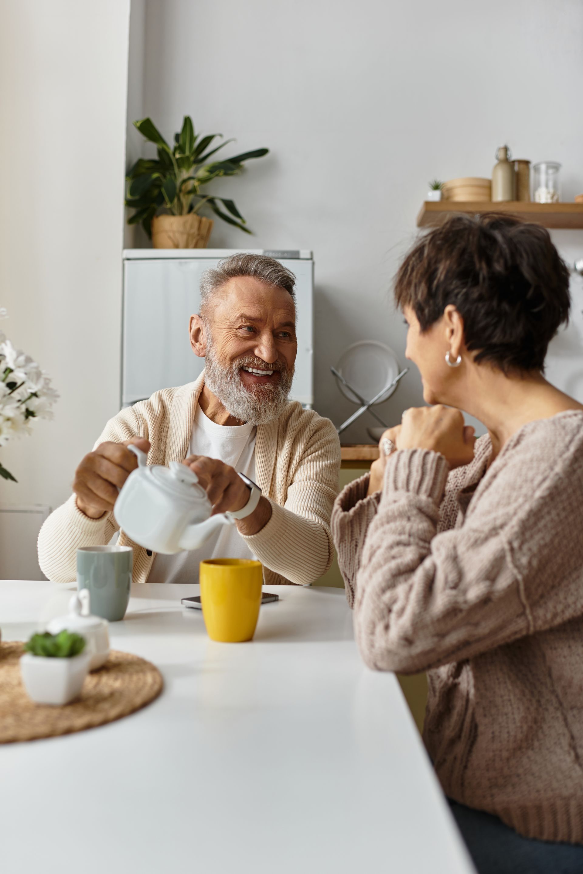 An elderly couple is sitting at a table drinking coffee.