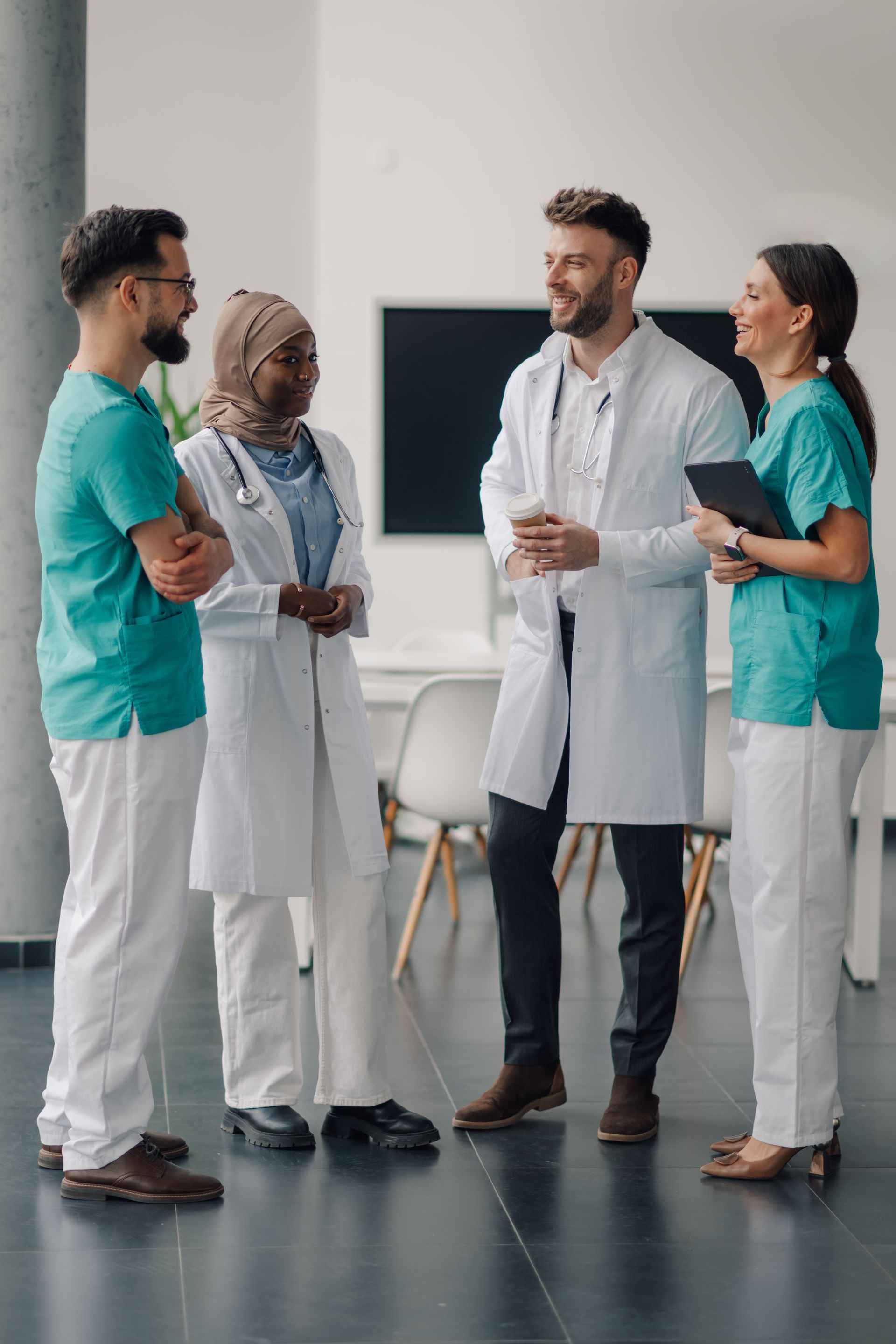 A group of doctors and nurses are standing next to each other in a hospital lobby.