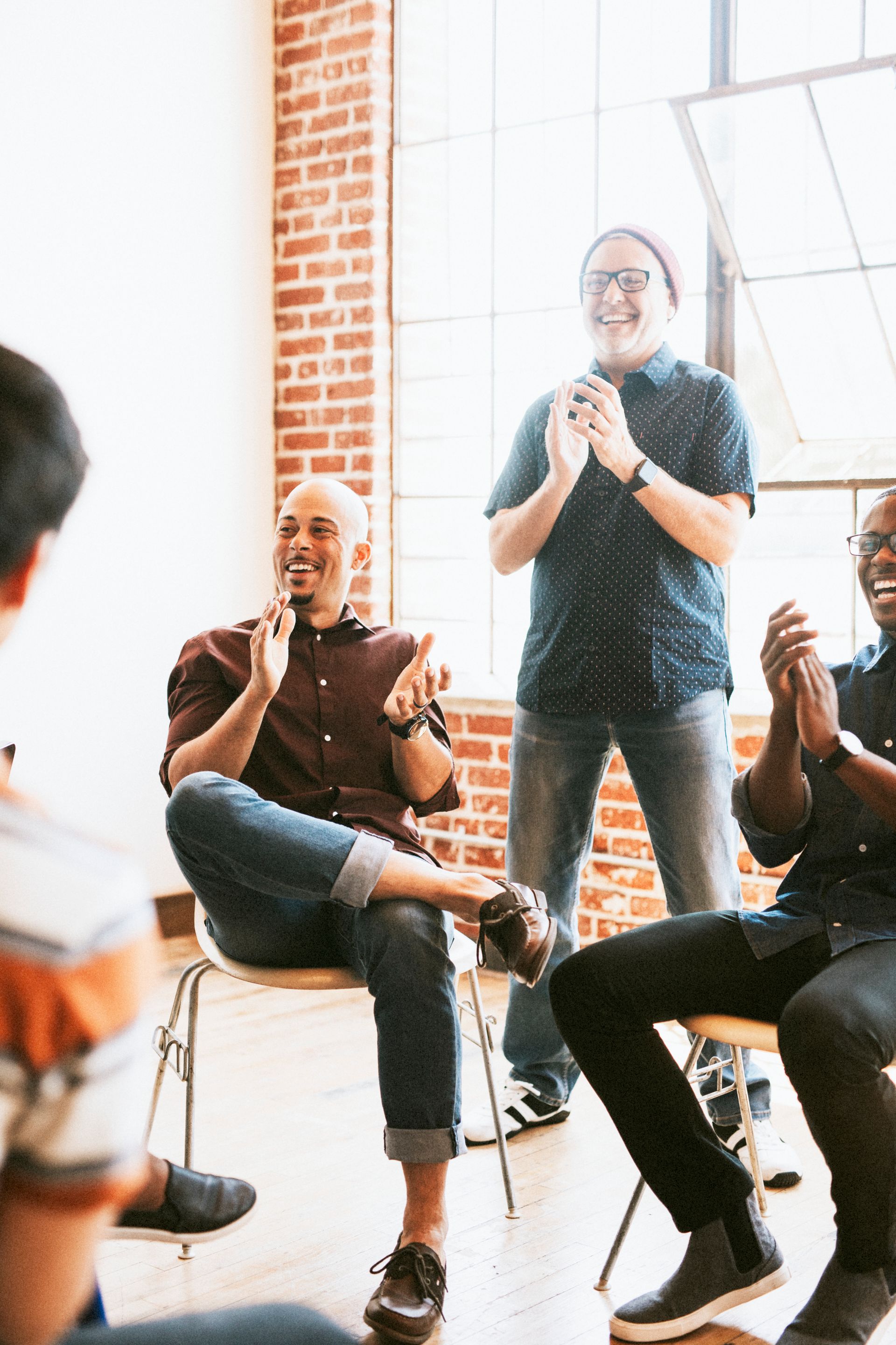 A group of men are sitting in a circle clapping their hands.