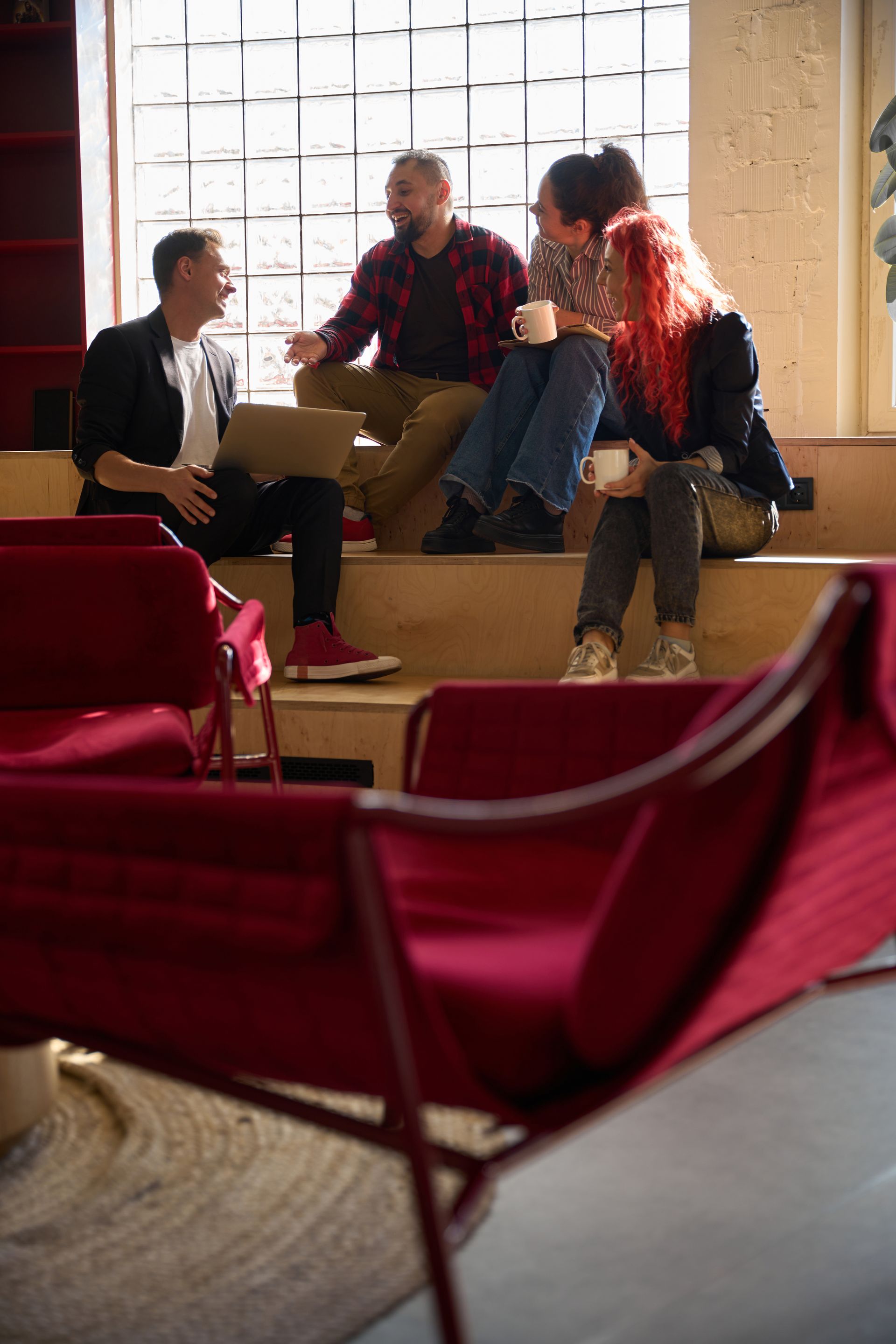 A group of people are sitting on a ledge talking to each other.