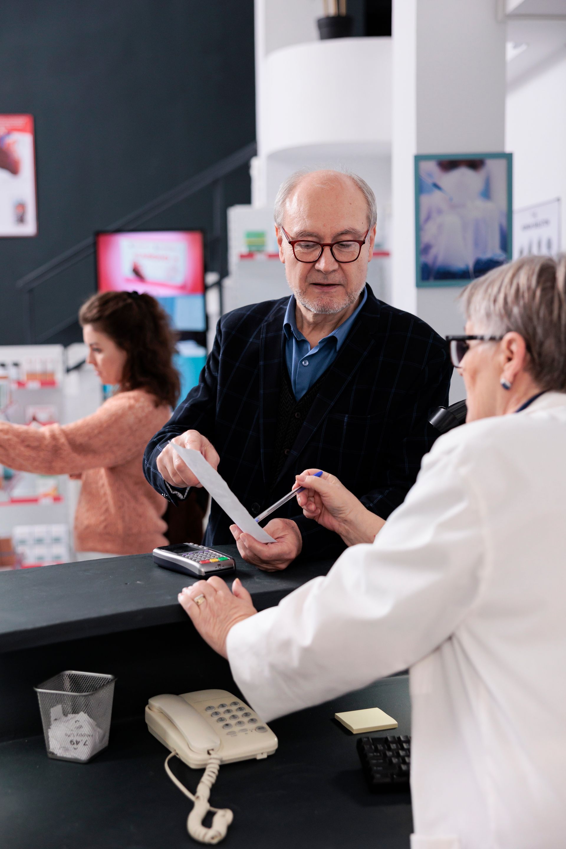 A man and a woman are standing at a counter in a pharmacy.