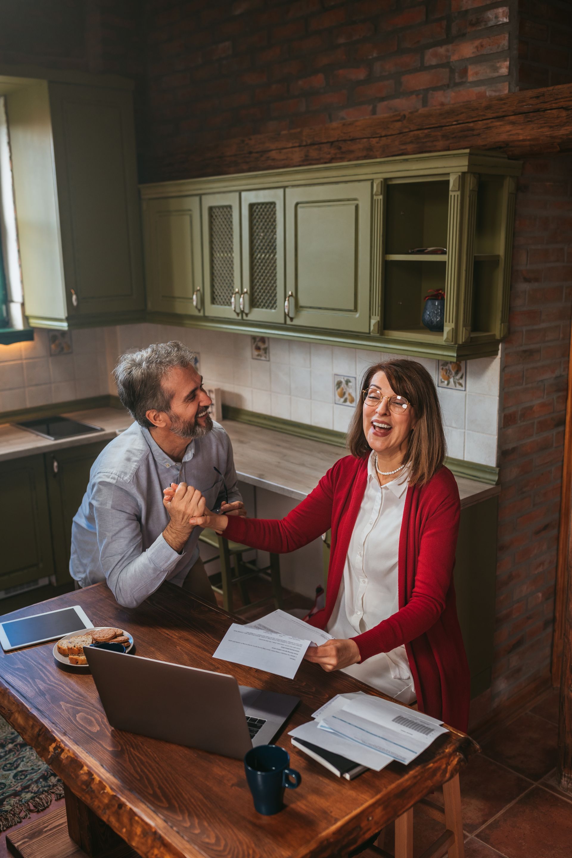 A man and a woman are sitting at a table with papers and a laptop.