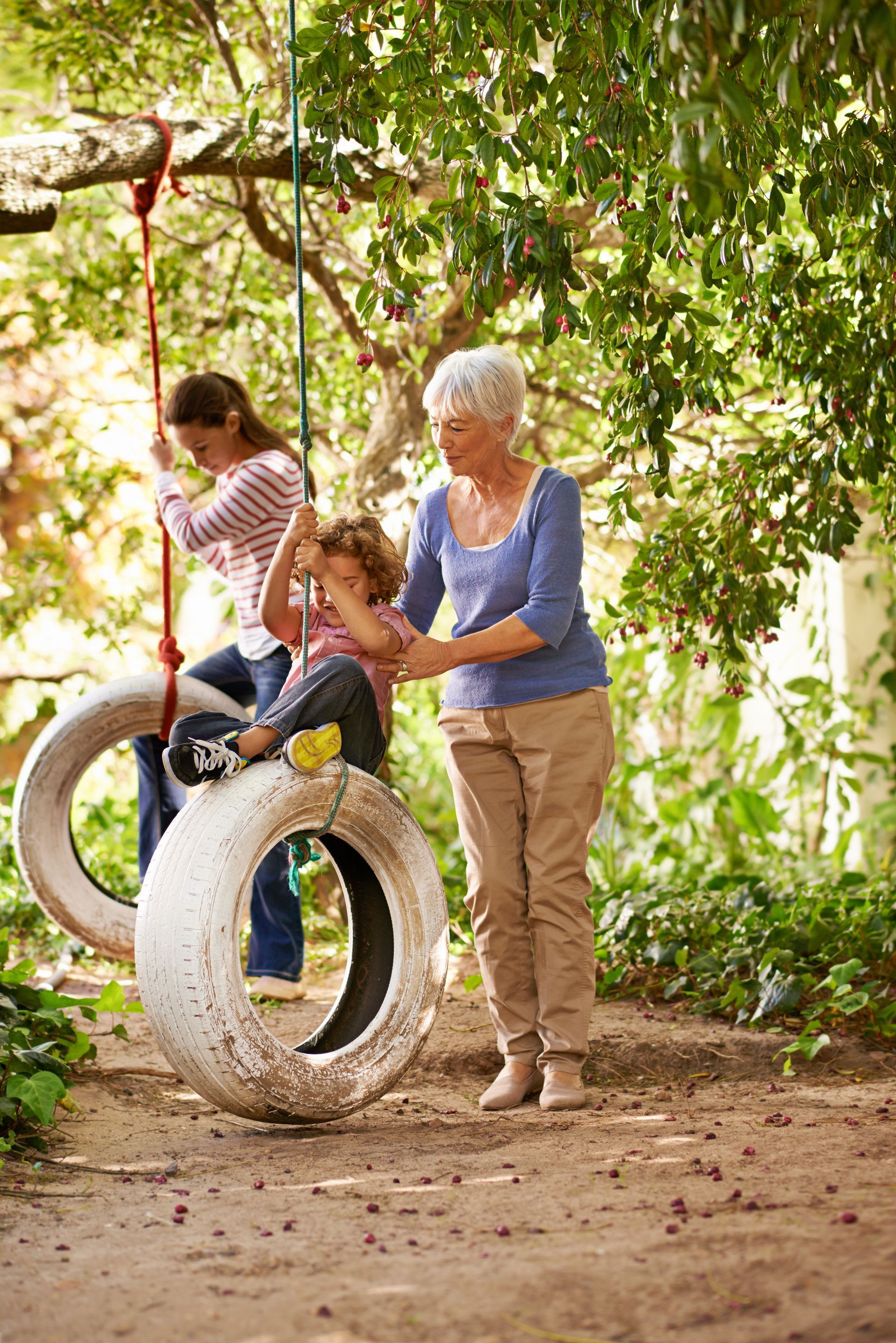 A woman is helping a child on a tire swing.