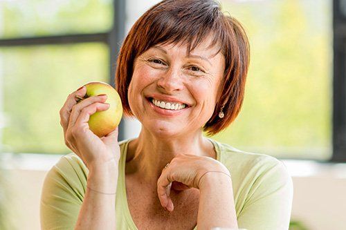 Older woman smiling while holding an apple