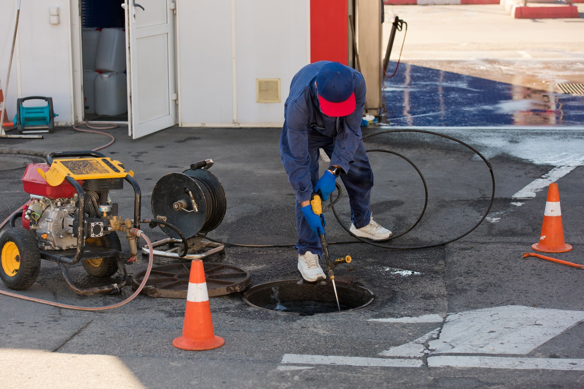 Worker in blue overalls, red cap, working on a sewer Worker in blue overalls, red cap, working on a sewer