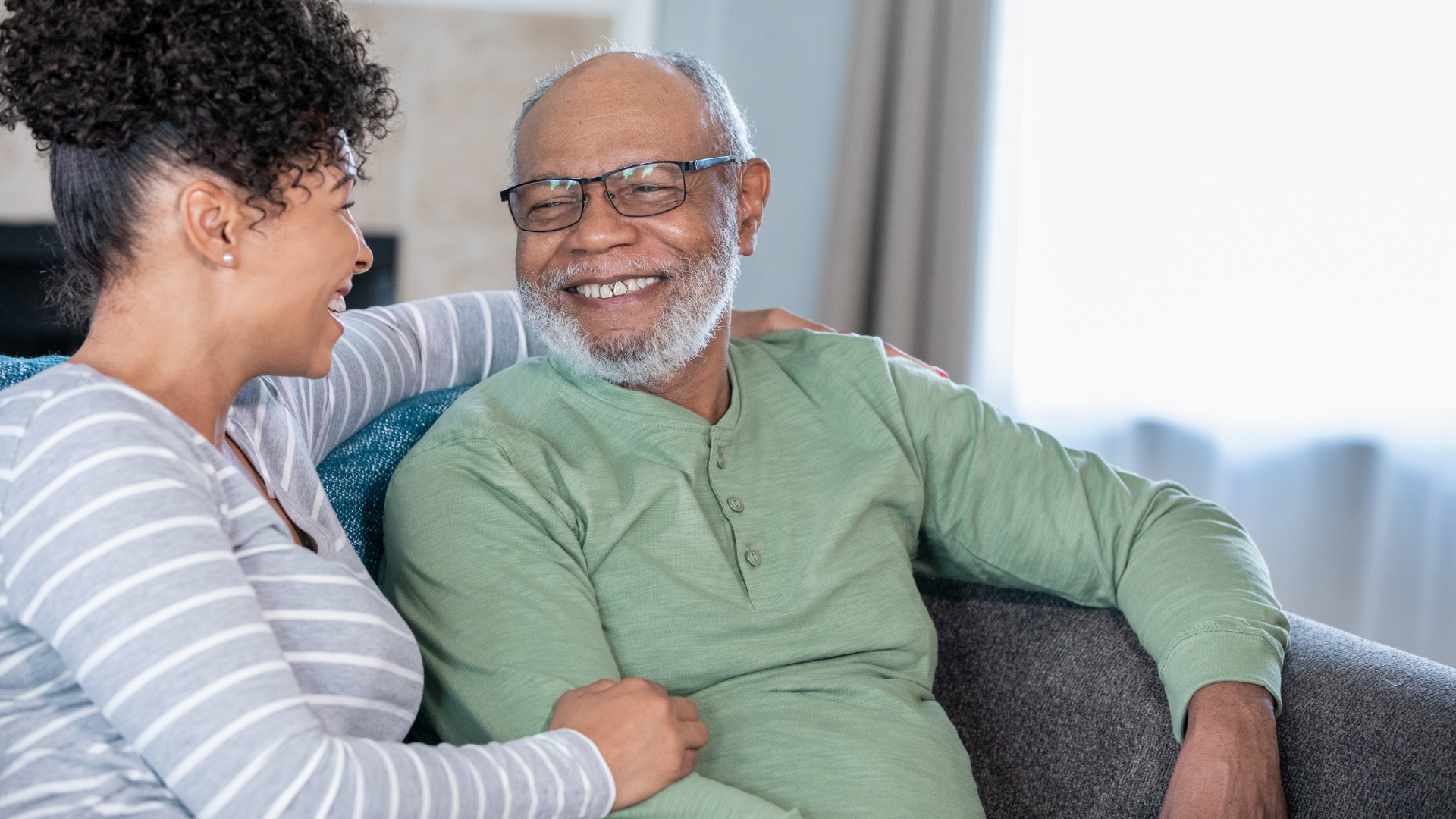A woman is sitting next to an older man on a couch.