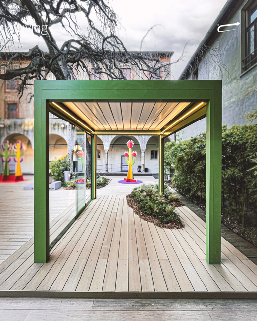 Un pergolato verde è situato sopra un ponte di legno in un cortile.