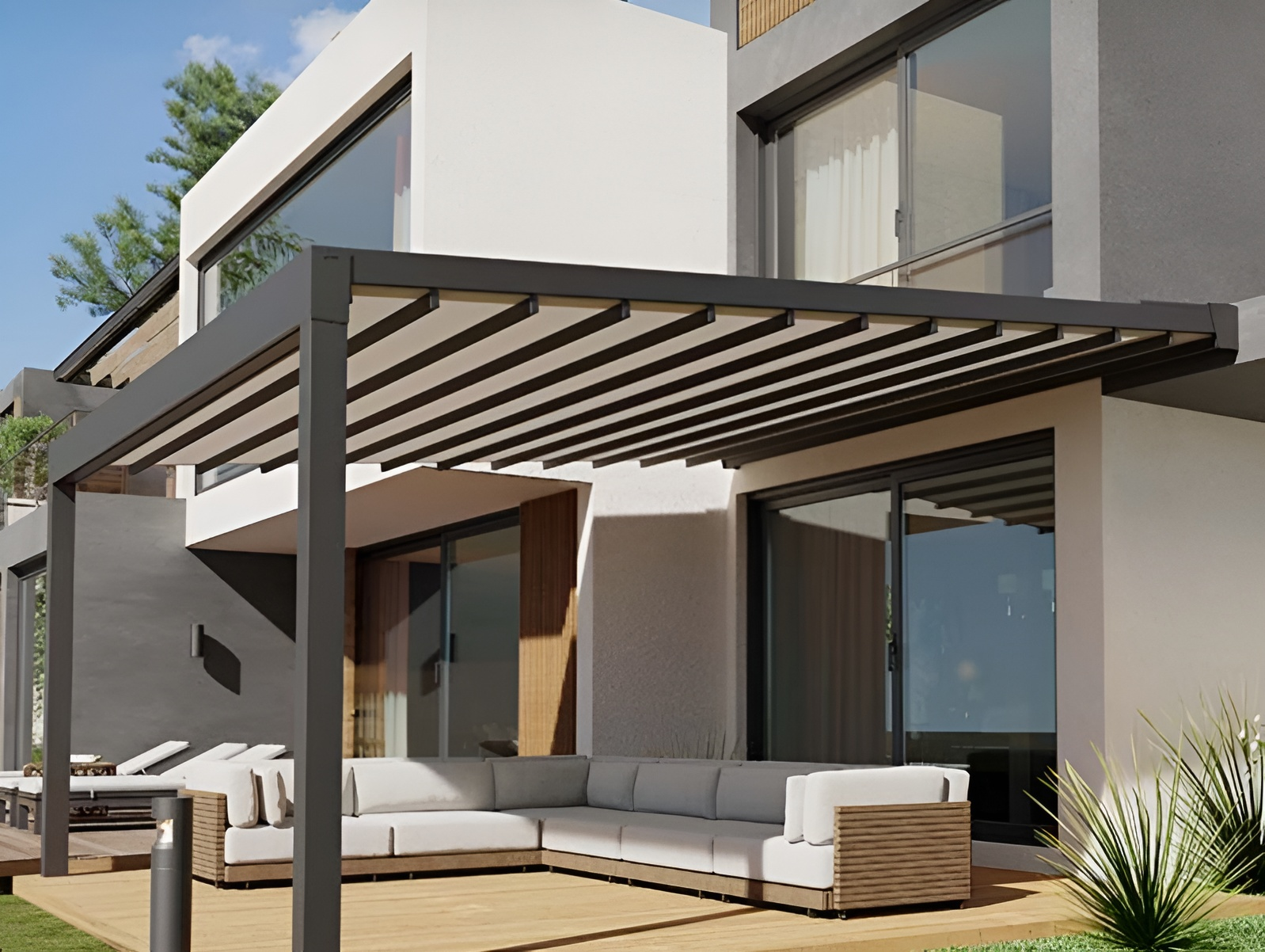 Una casa moderna con un pergolato e un divano nel patio.