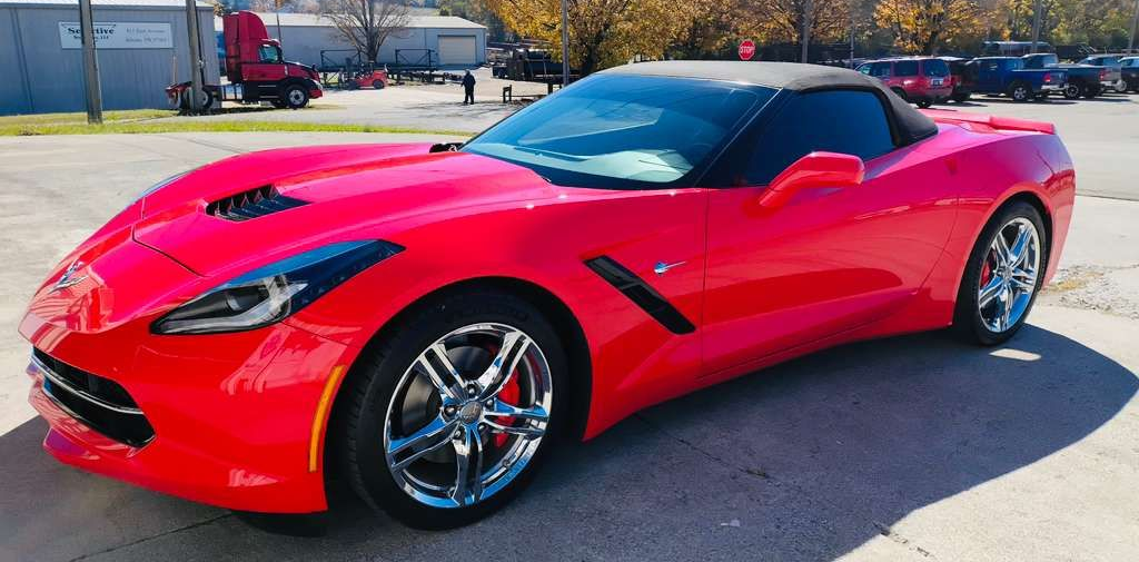 Red convertible Corvette parked outside on a sunny day.