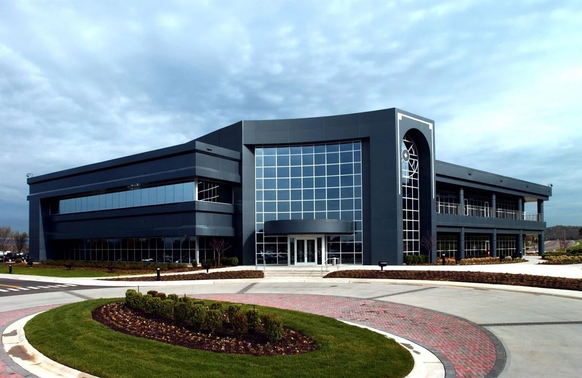 Dark gray modern office building with large windows and circular driveway.