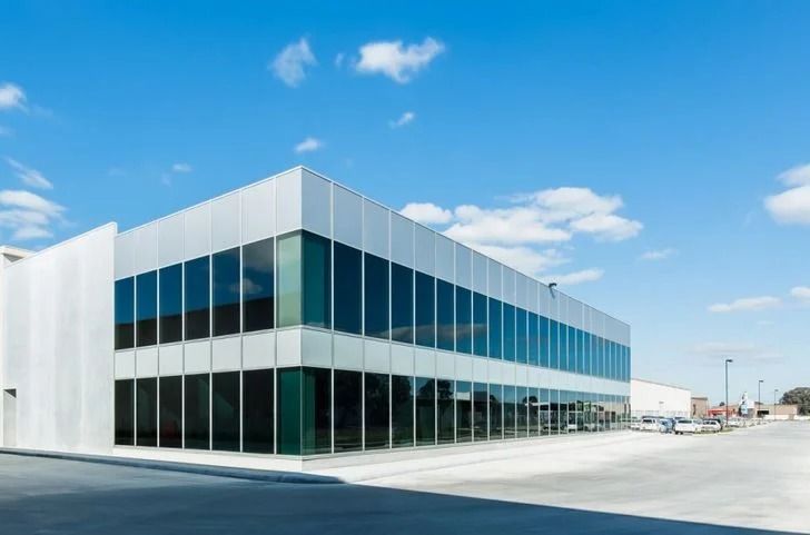 Modern commercial building with large windows and a bright blue sky.