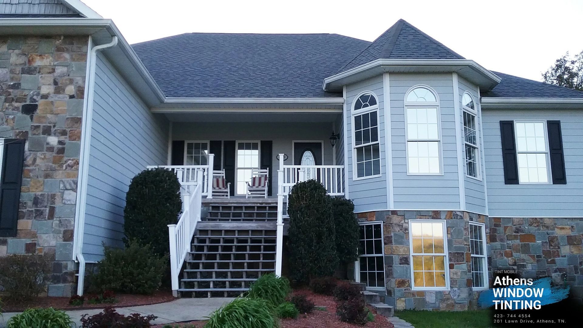 House exterior with light blue siding, stone accents, and tinted windows.