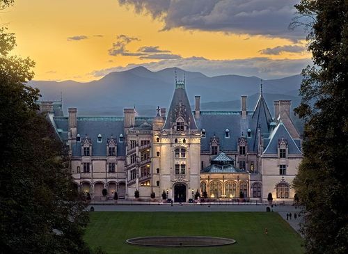 Black van on a road near a lake, mountains, and trees in black and white.