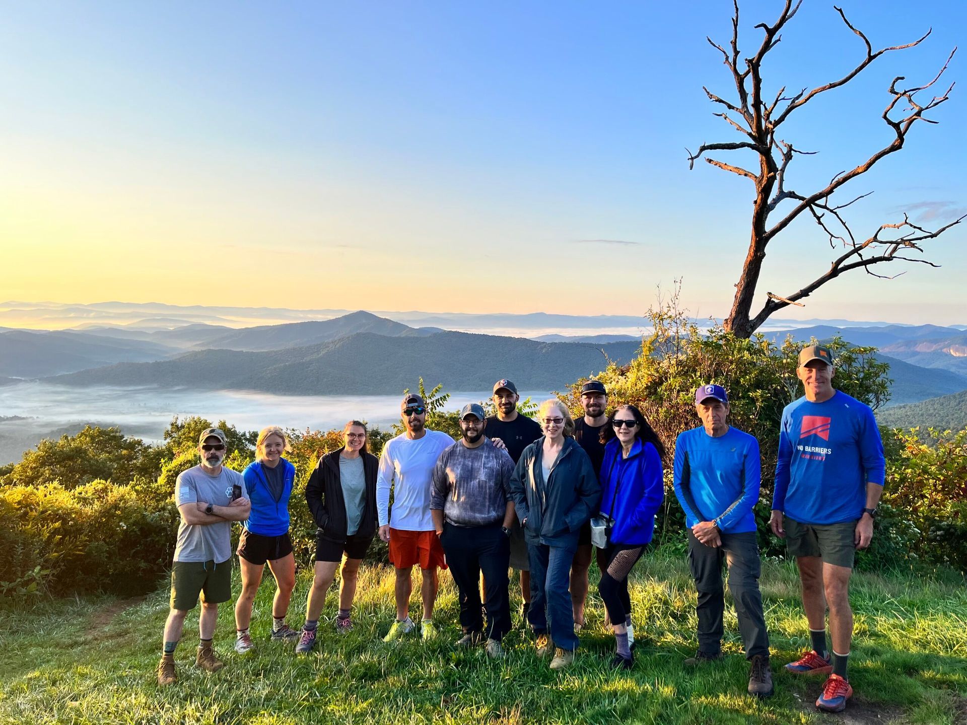Group of people atop a mountain with a scenic view.  Sunrise sky and landscape.
