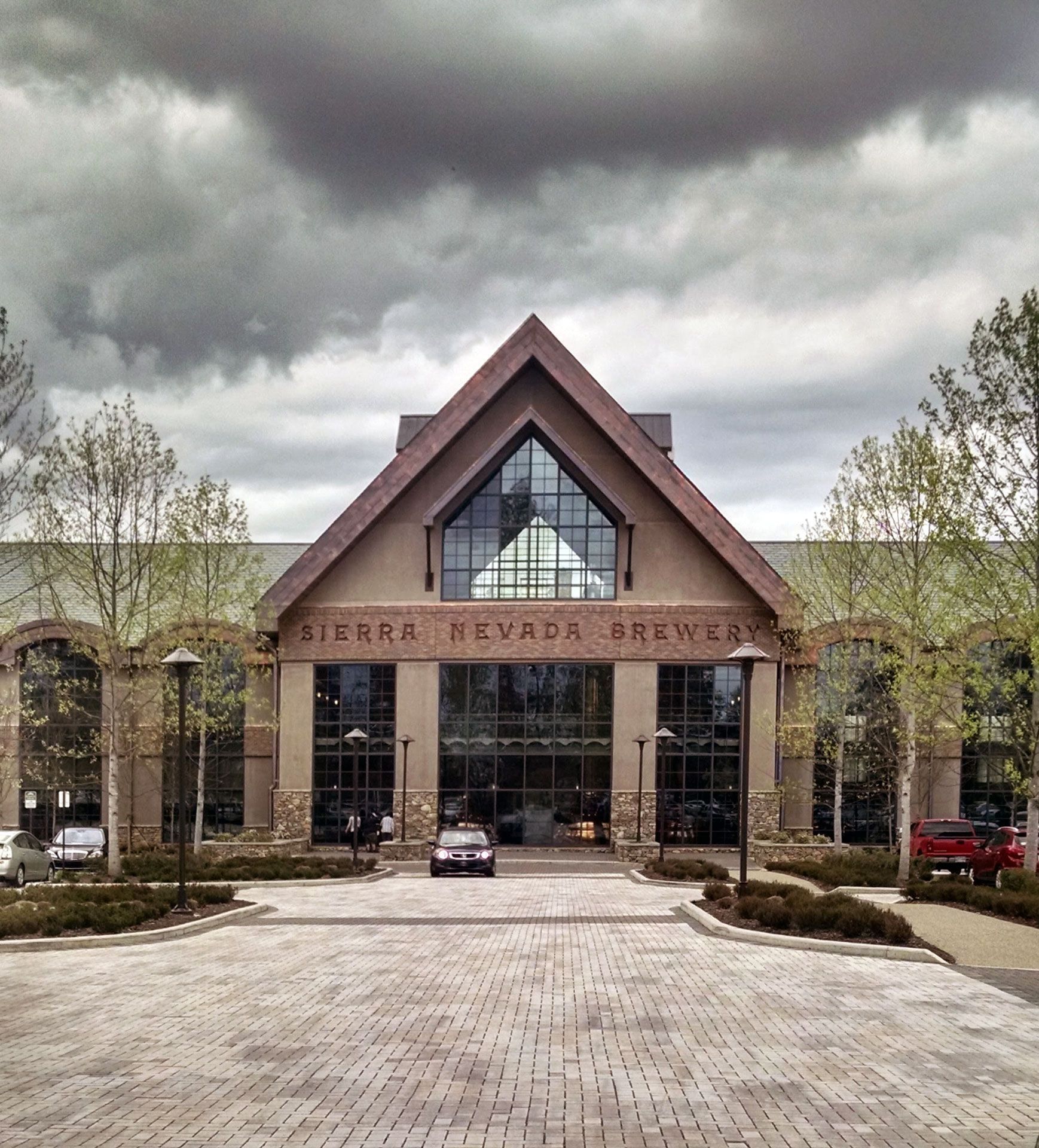 Two hands clink beer glasses in a toast, amber liquid with white foam, people in a pub setting.