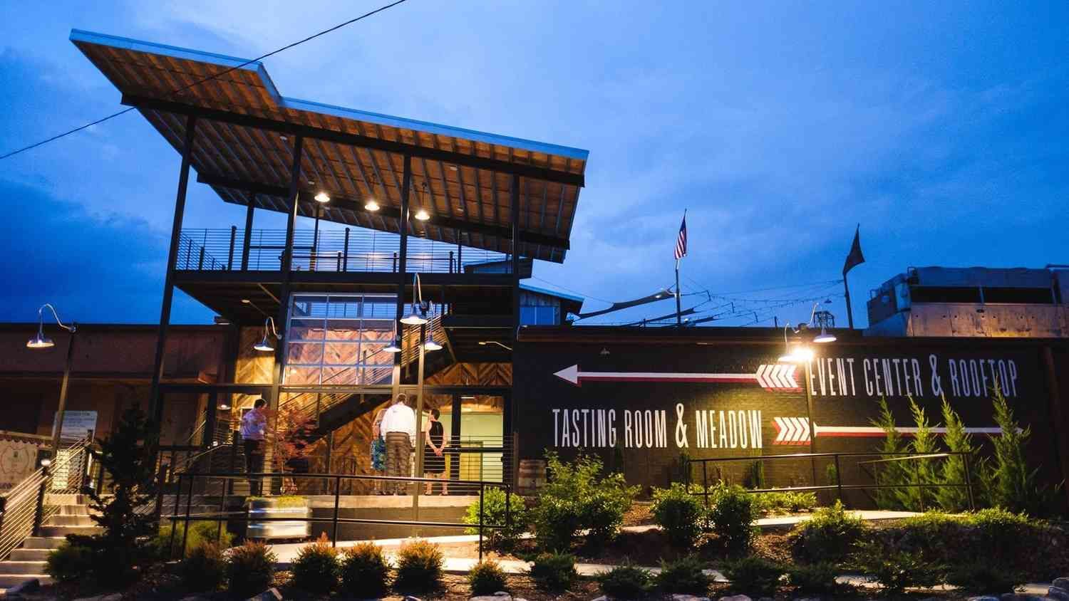 Highland Brewing Event Center entrance at dusk with lit sign and flag.