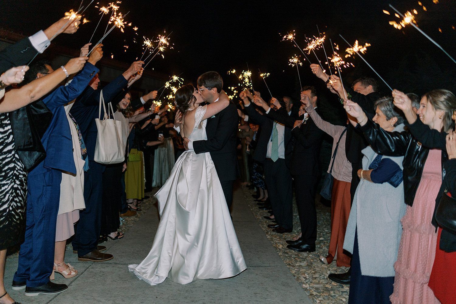 Couple kisses beneath sparklers held by wedding guests at a venue in Asheville, NC.