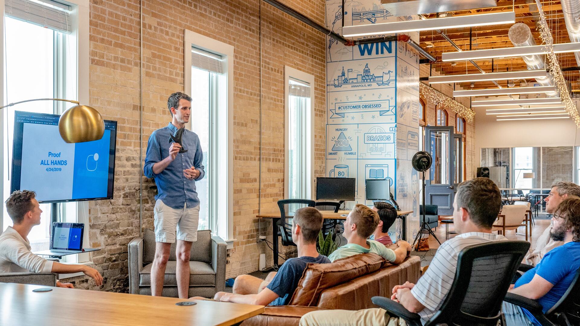 A team meeting with one presenter in front of a tv board.