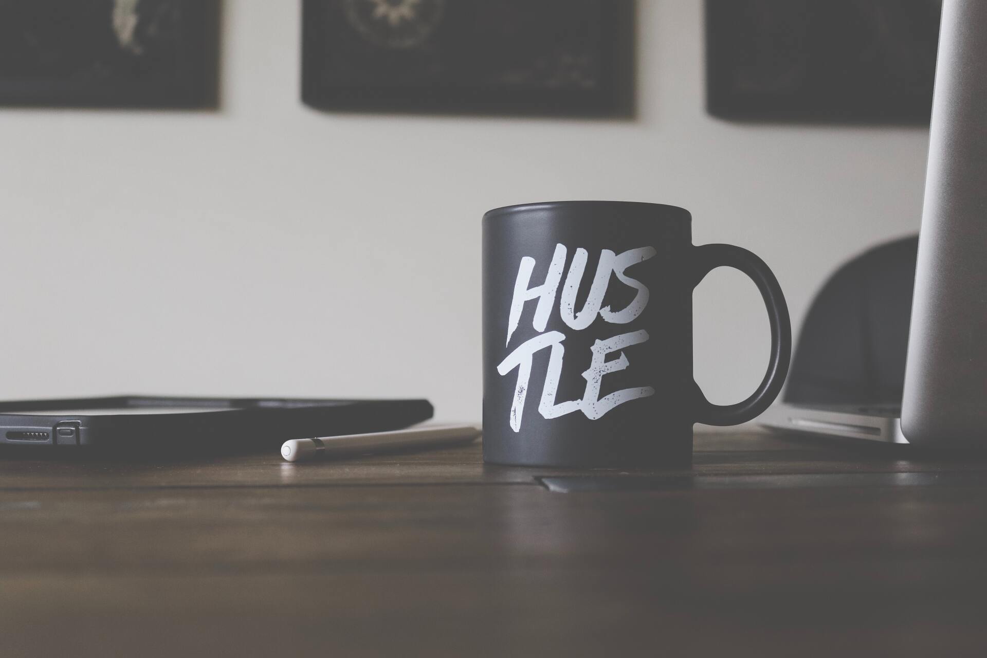 Hustle mug on a desk next to a laptop