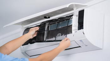 A person is cleaning the filter of an air conditioner.