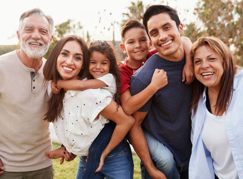 A large family is posing for a picture together in a park.