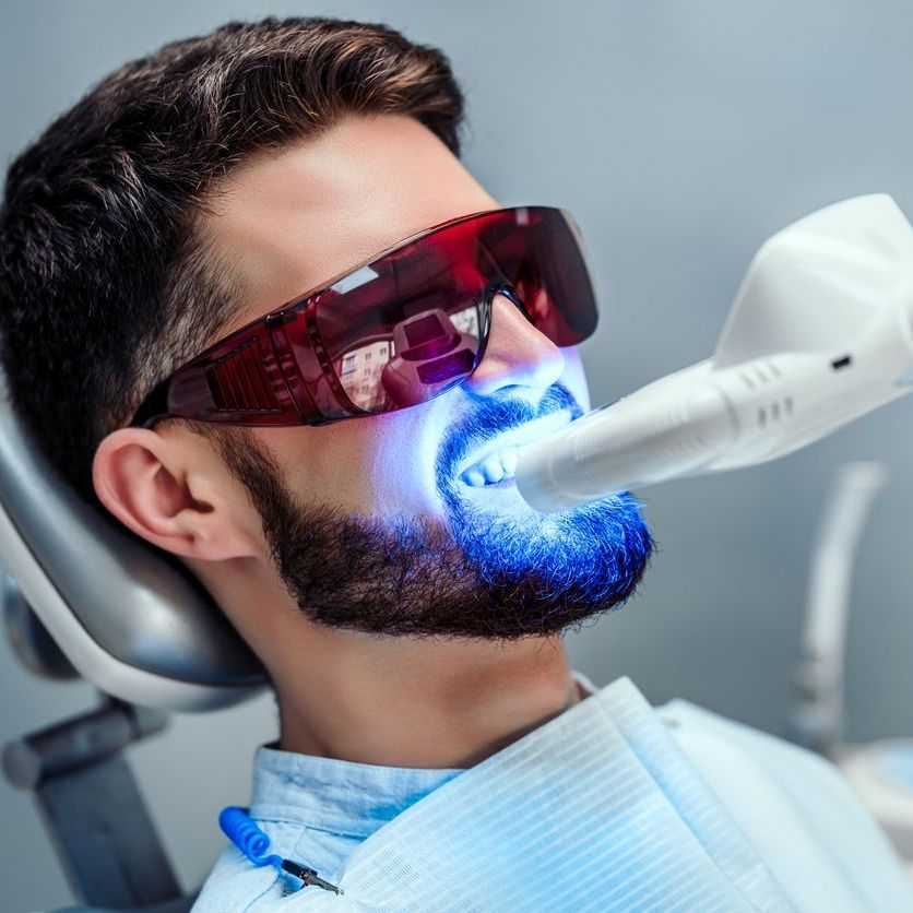 A man is getting his teeth whitened by a dentist