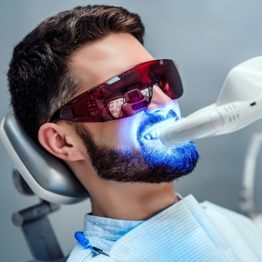A man is getting his teeth whitened by a dentist