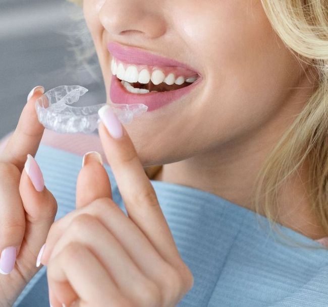 A woman is holding a clear brace in her mouth.