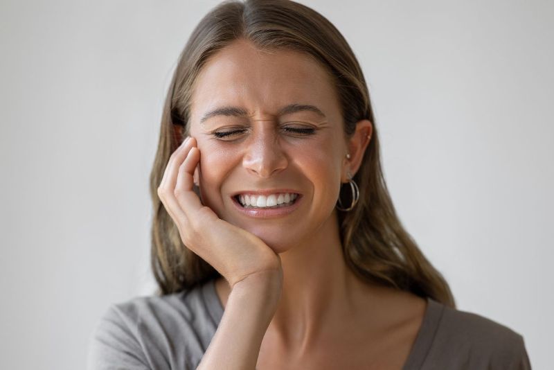 A woman is holding her face in pain because of a toothache.