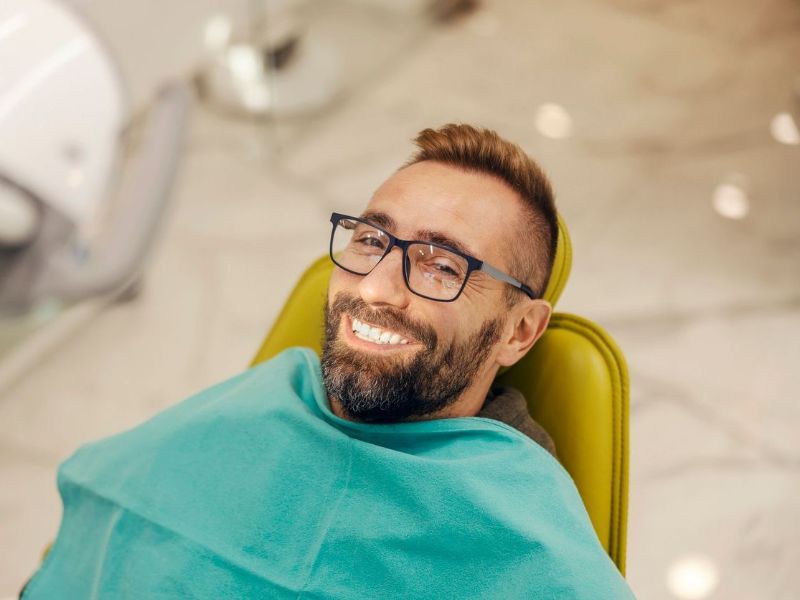 A man is smiling while sitting in a dental chair.