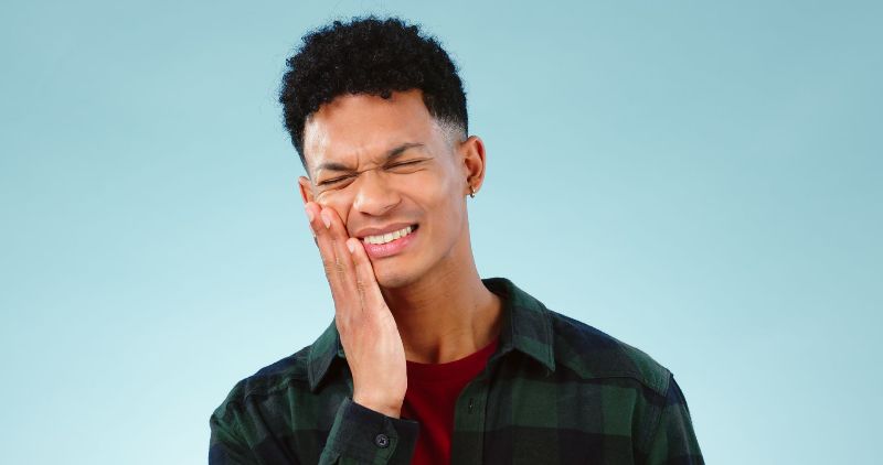 A young man is holding his face in pain because of a toothache.