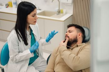 Woman in dentist chair with smile, teeth shade chart in front of teeth.