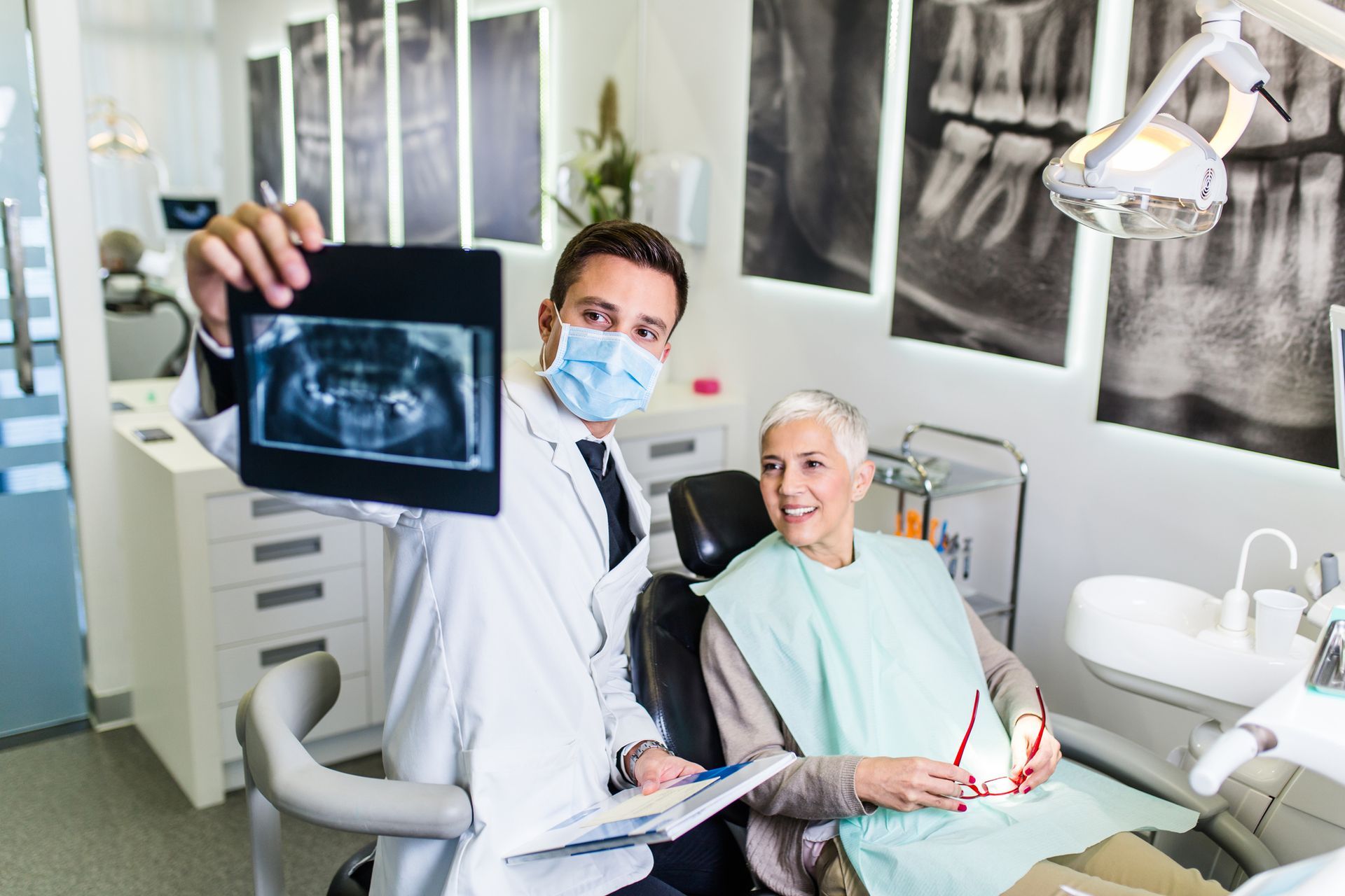 A dentist is holding an x-ray of a patient 's teeth in a dental office.