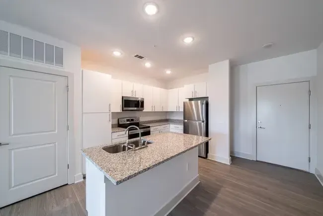 Modern white kitchen with island, stainless steel appliances, and granite countertops.