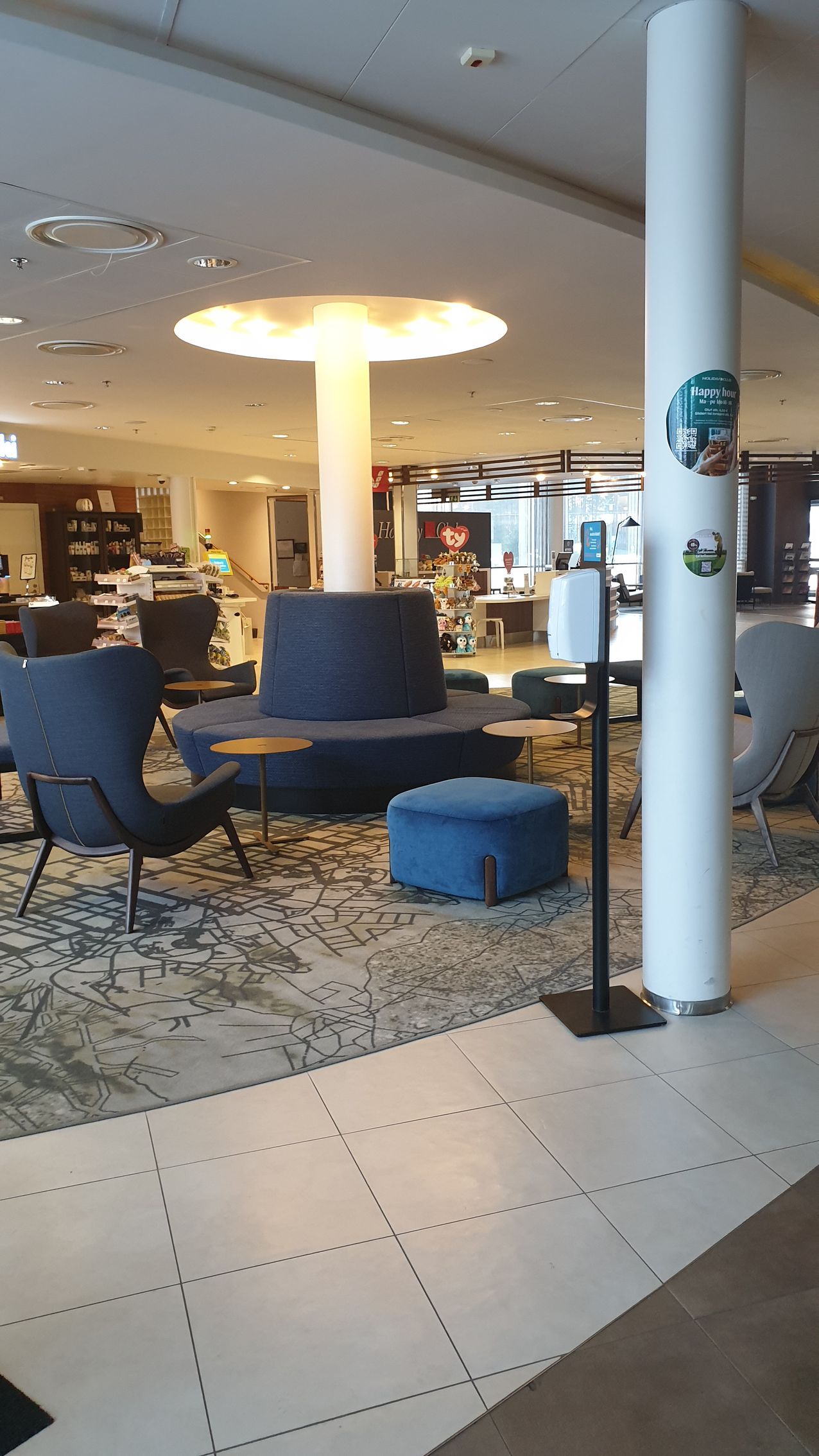 There are many chairs and ottomans in the lobby of a hotel