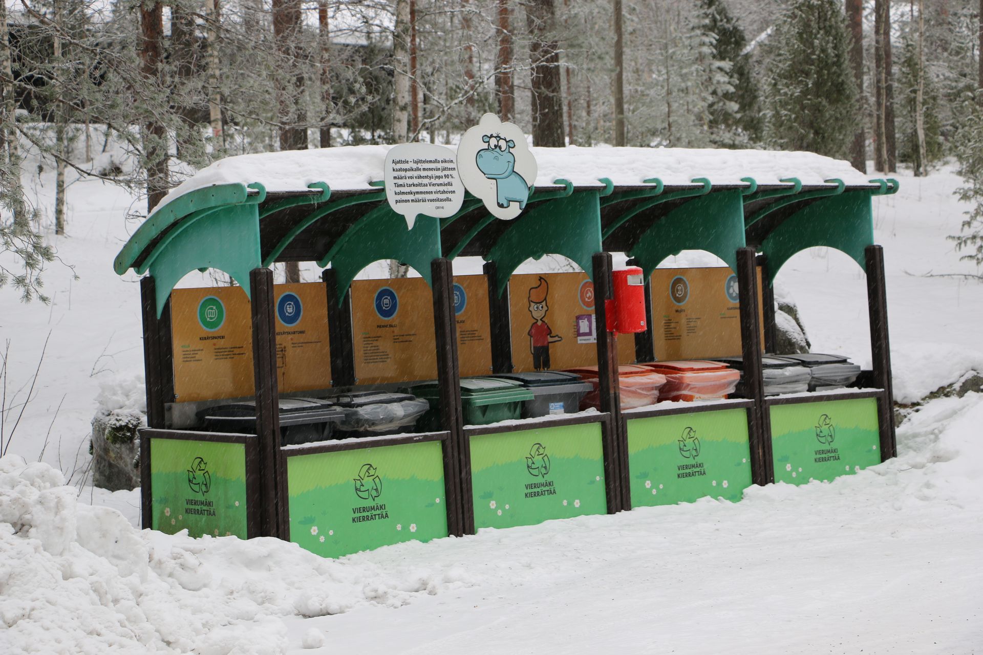 A row of recycling bins are lined up in the snow.
