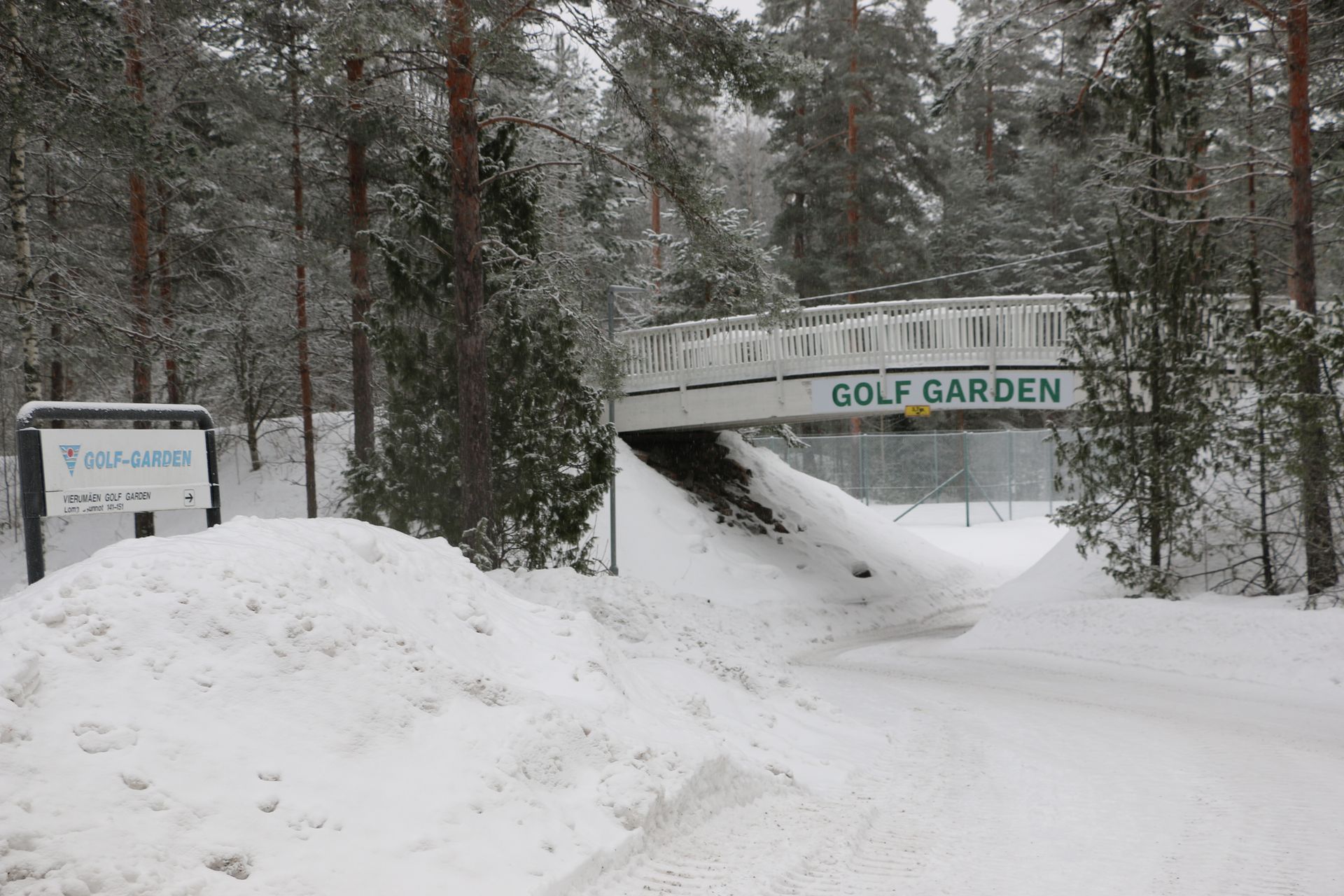 A bridge over a snowy road that says golf garden