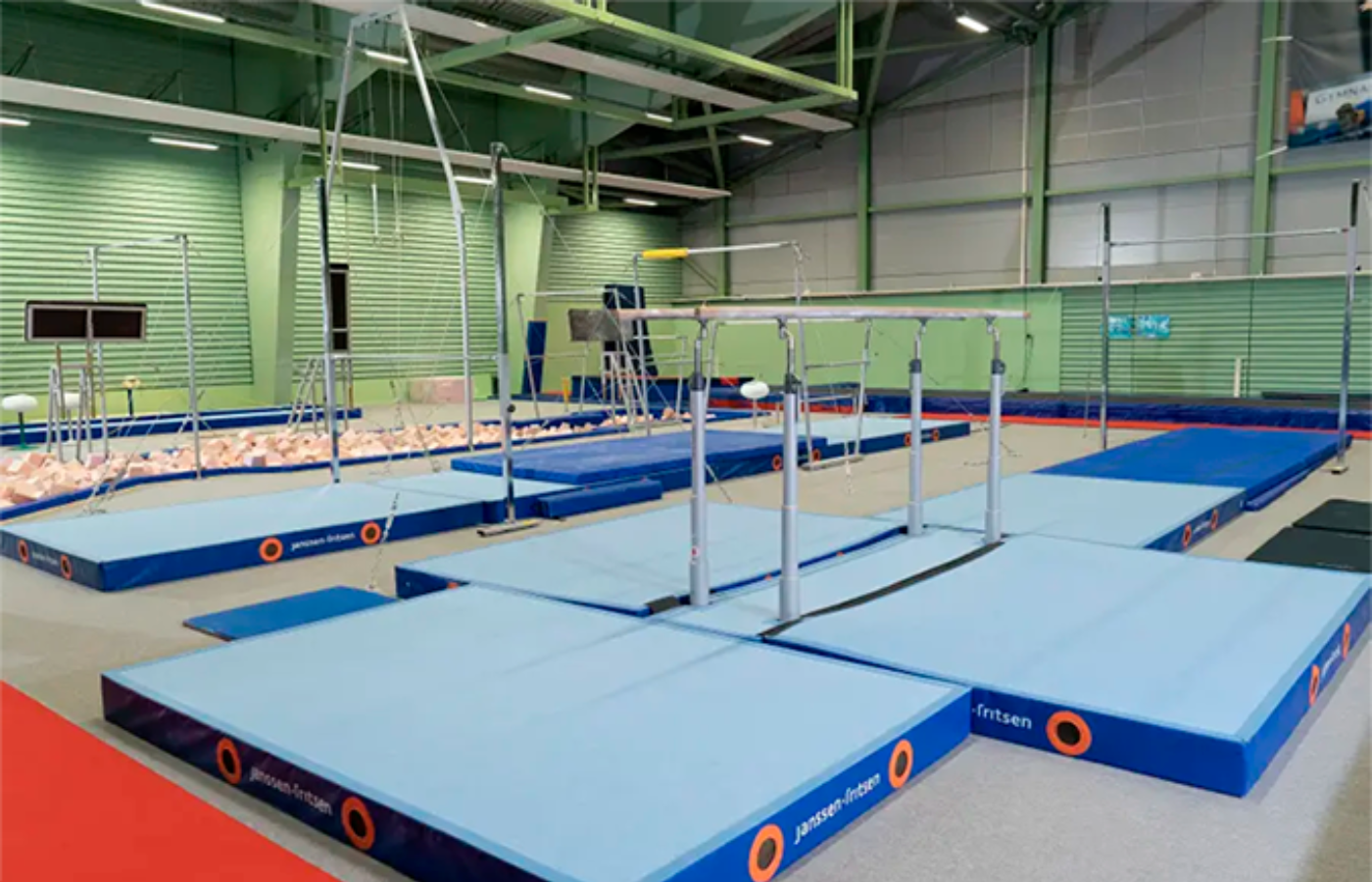 A gym with a lot of blue mats and bars