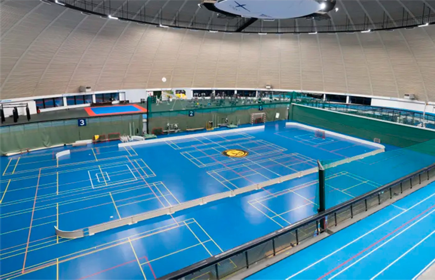 A large indoor tennis court with a volleyball net