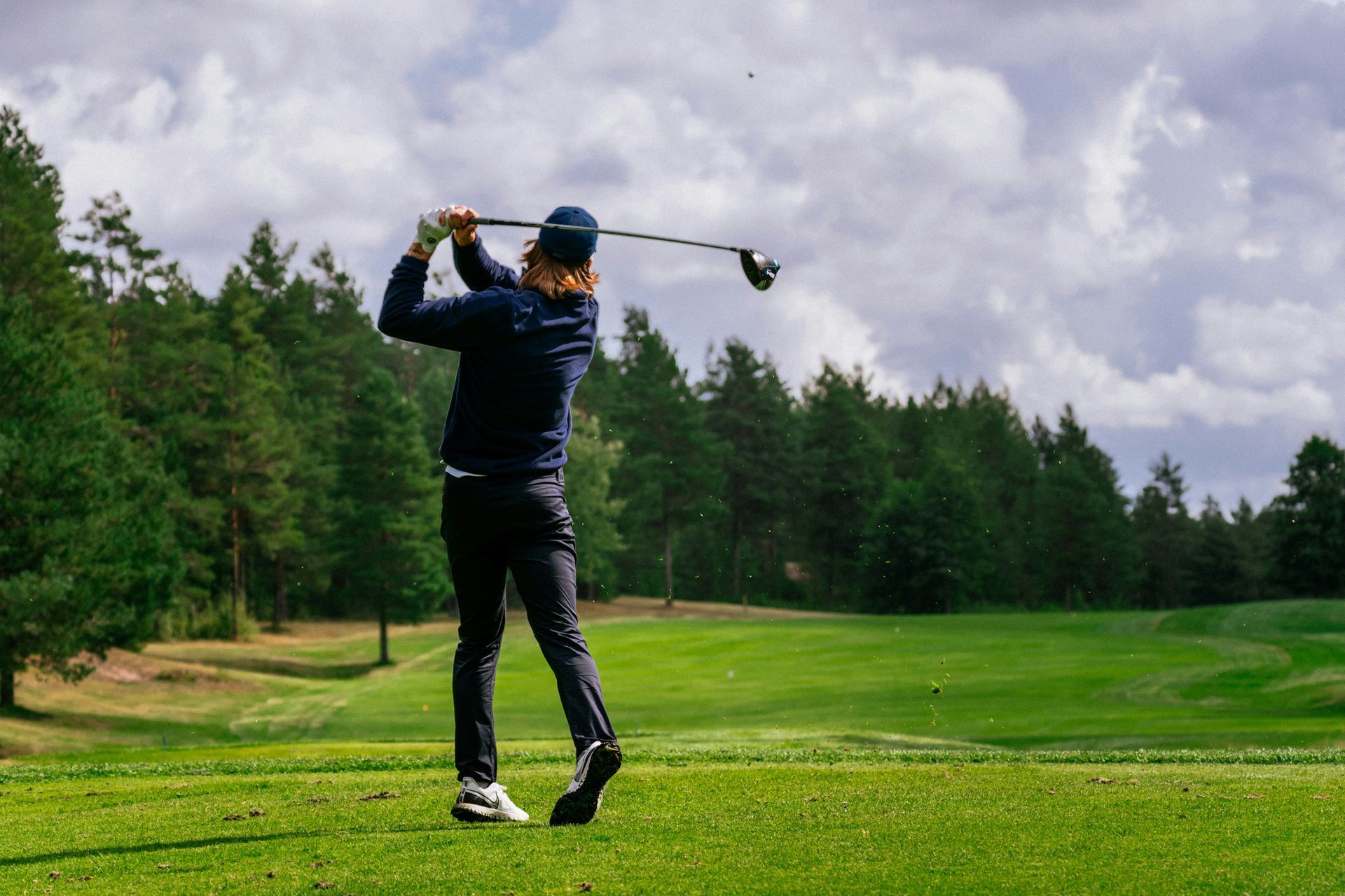 A man is swinging a golf club on a golf course.