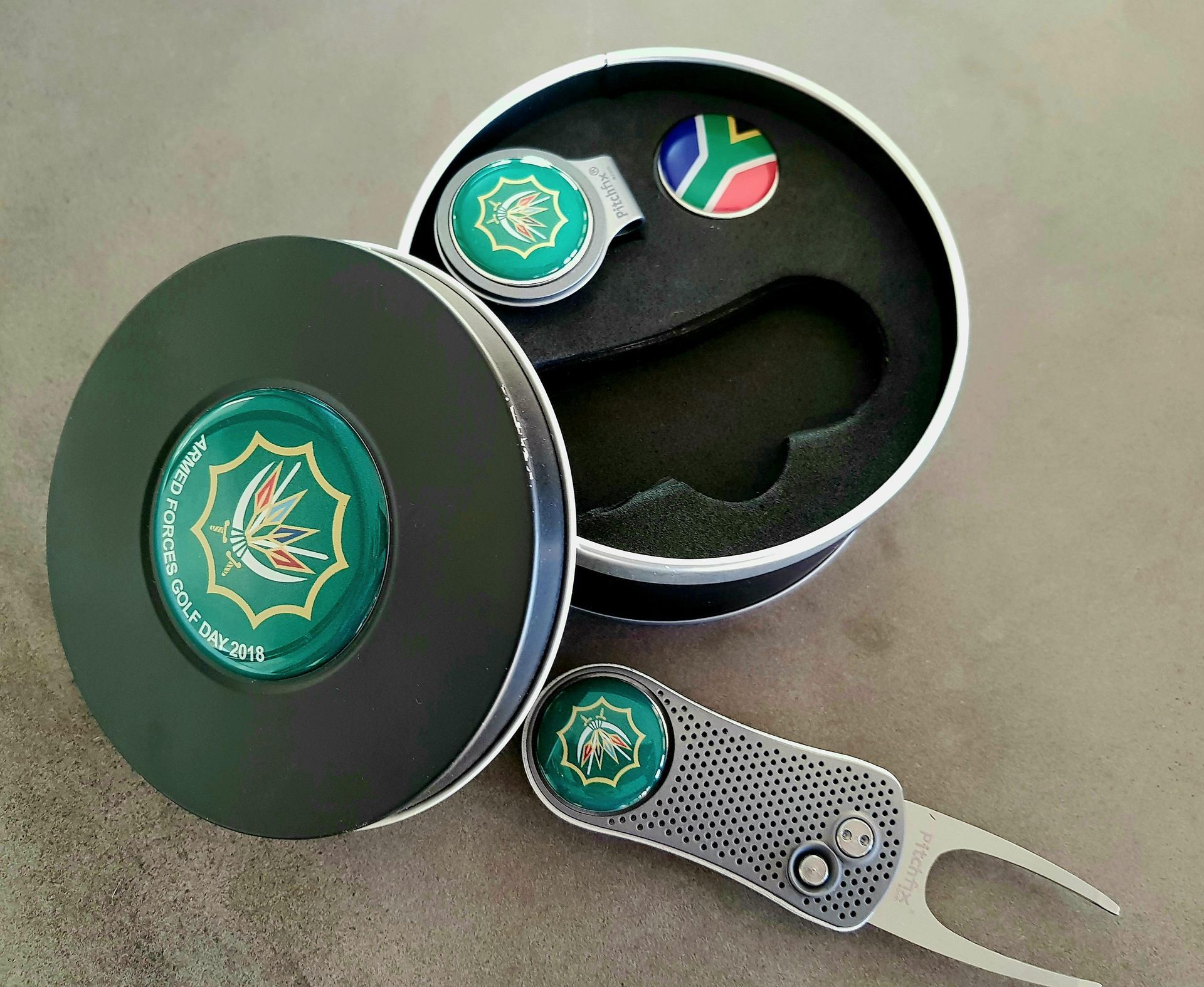 A golf ball marker and pitchfork in a tin supplied by BlinC Corporate.