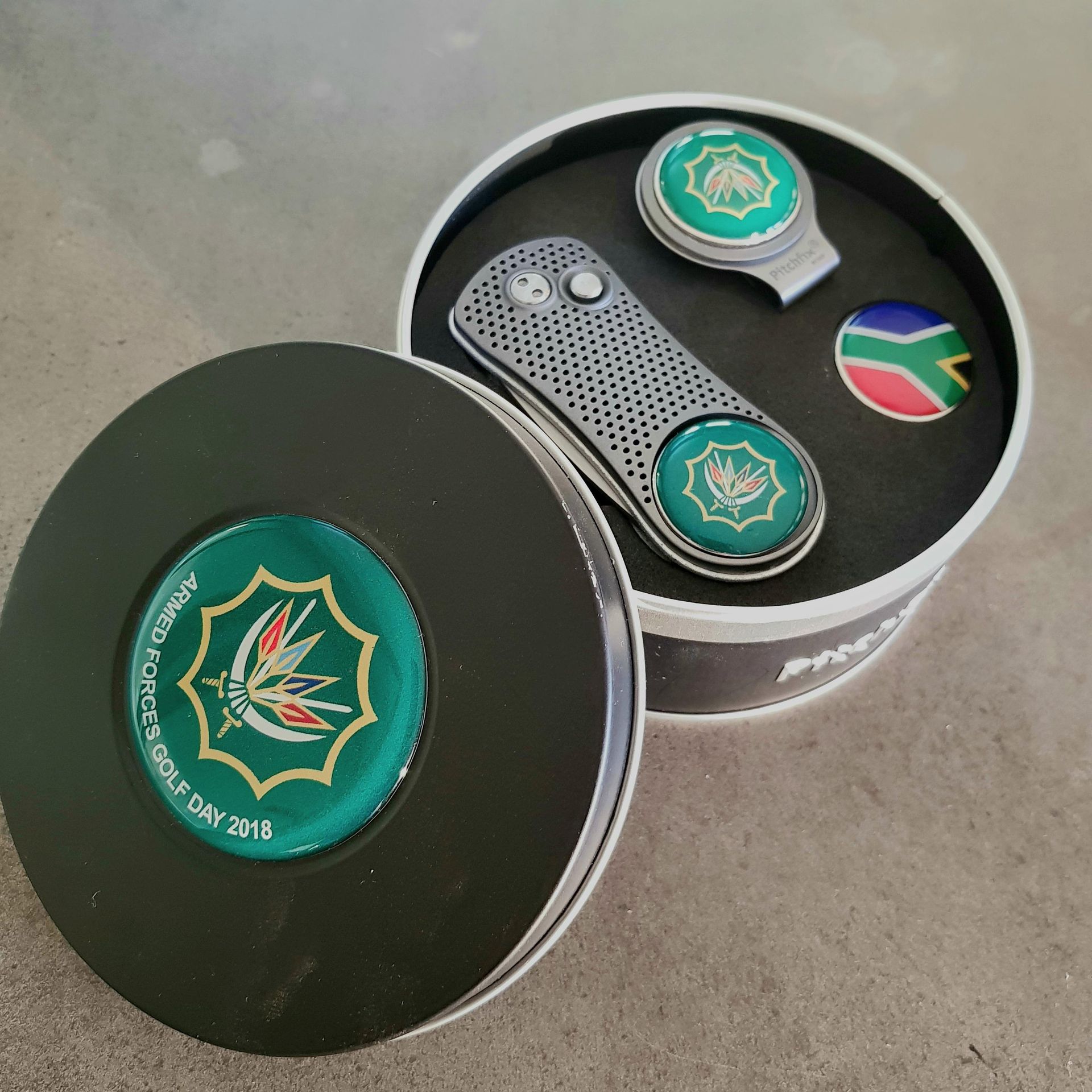 A golf ball marker in a black tin supplied by BlinC Corporate.