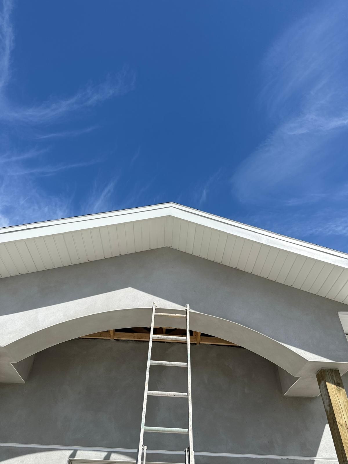 A ladder is sitting under the roof of a building under construction.