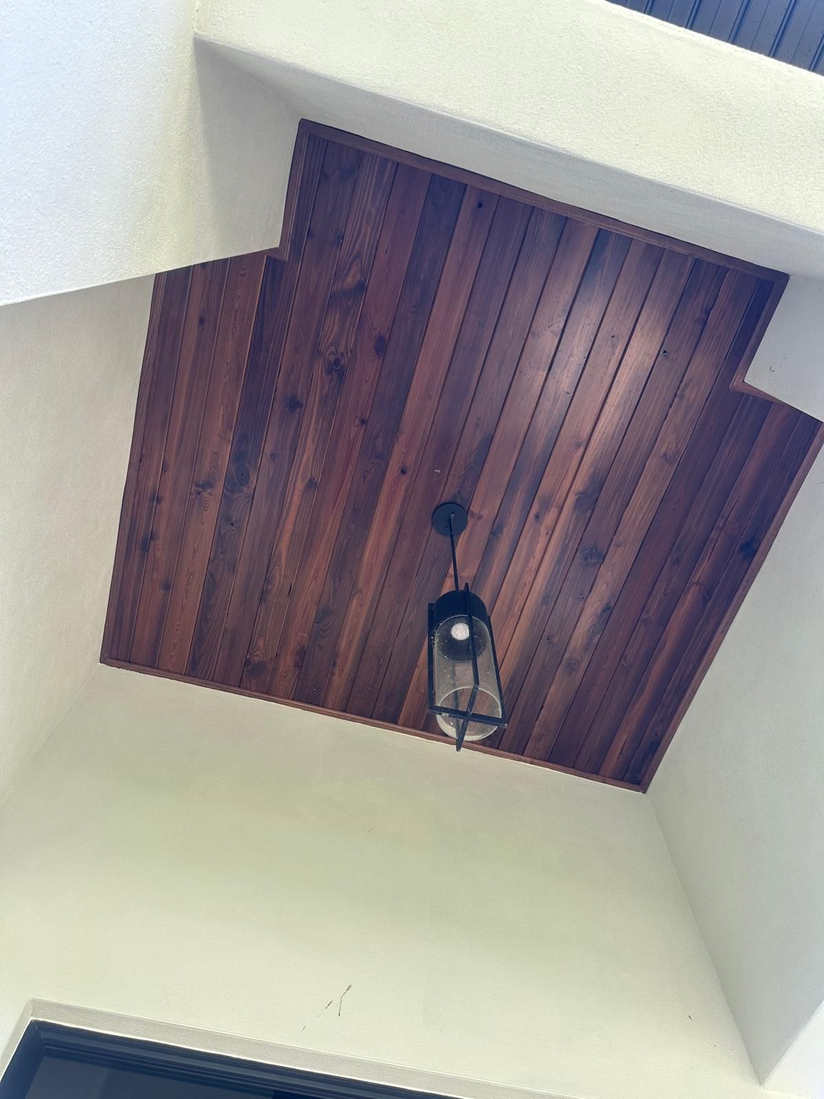 A wooden ceiling with a light hanging from it